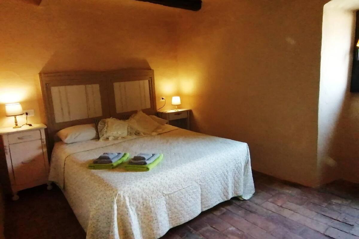 A cozy bedroom with a bed, two bedside lamps, and a wooden headboard.