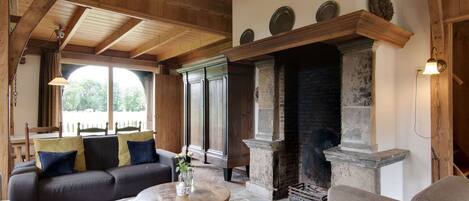 A cozy living room with a fireplace, wooden ceiling, and comfortable seating.