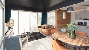 Una sala de estar moderna con un sofá, una mesa de comedor y un ventanal con cortinas.