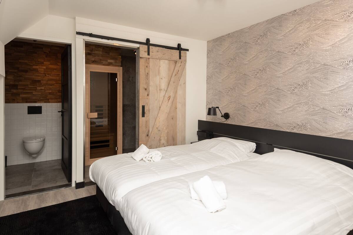 A modern bedroom with a large bed, a wooden door, and a patterned wall.