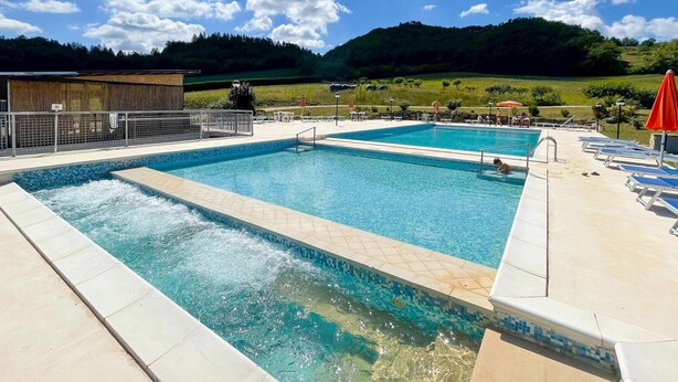 Een zwembad met betegelde rand en een apart gedeelte voor een jacuzzi.