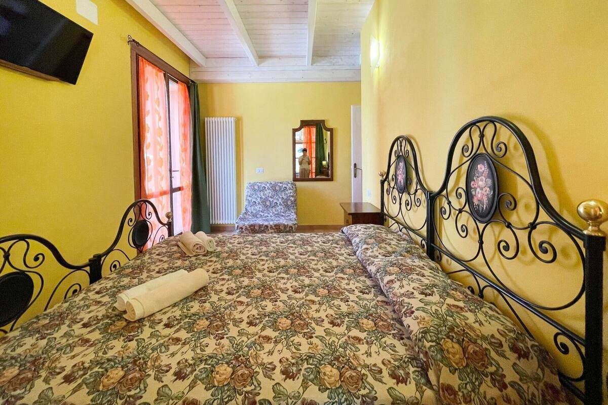 A room with a bed, a chair, a mirror, and a television.