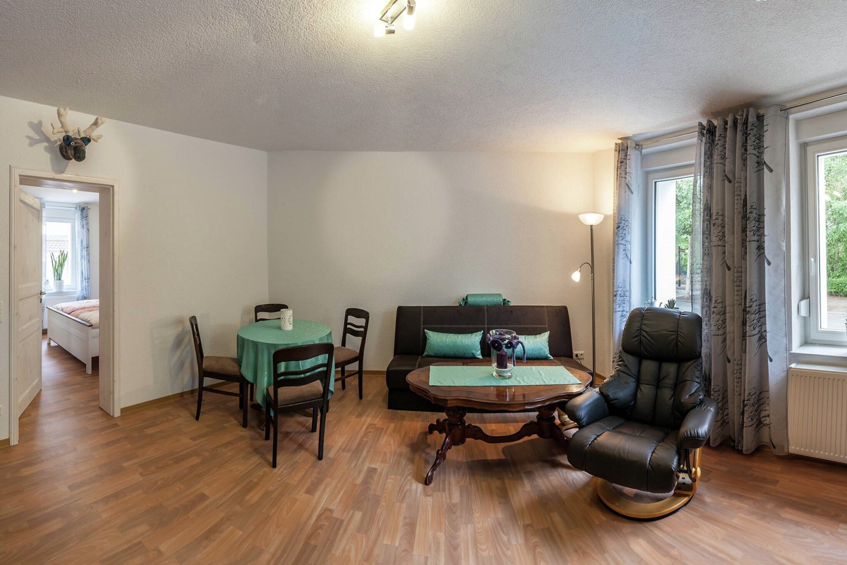 Une pièce comprenant une table à manger, des chaises, un canapé, un fauteuil de massage et une fenêtre avec des rideaux.