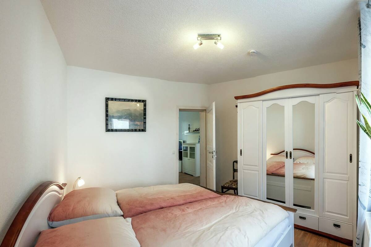 A bedroom with a bed, a wardrobe, and a framed picture on the wall.