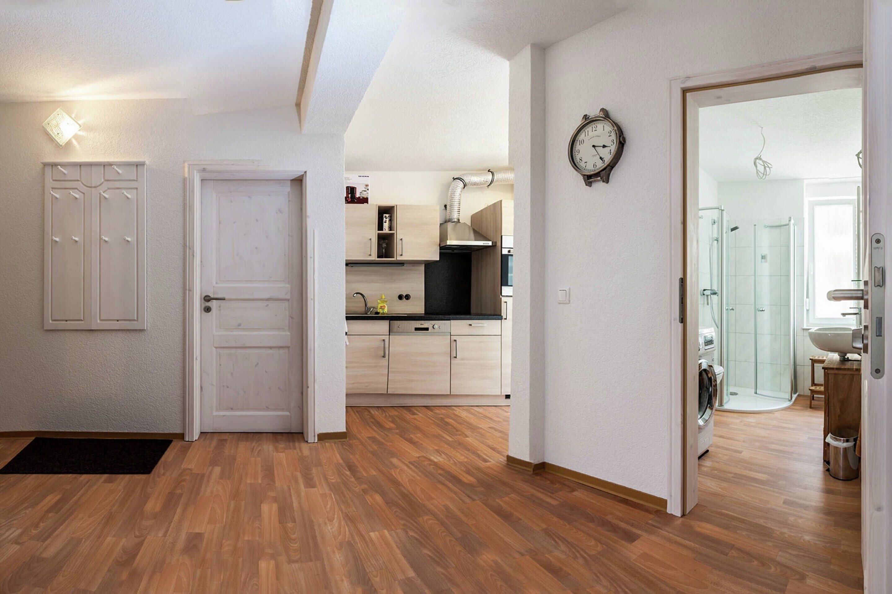 Een moderne keuken met lichte houten kastjes, een zwart aanrecht en een inbouwoven.