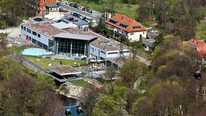 Un edificio moderno con fachada de vidrio, piscina y un sistema de teleférico.