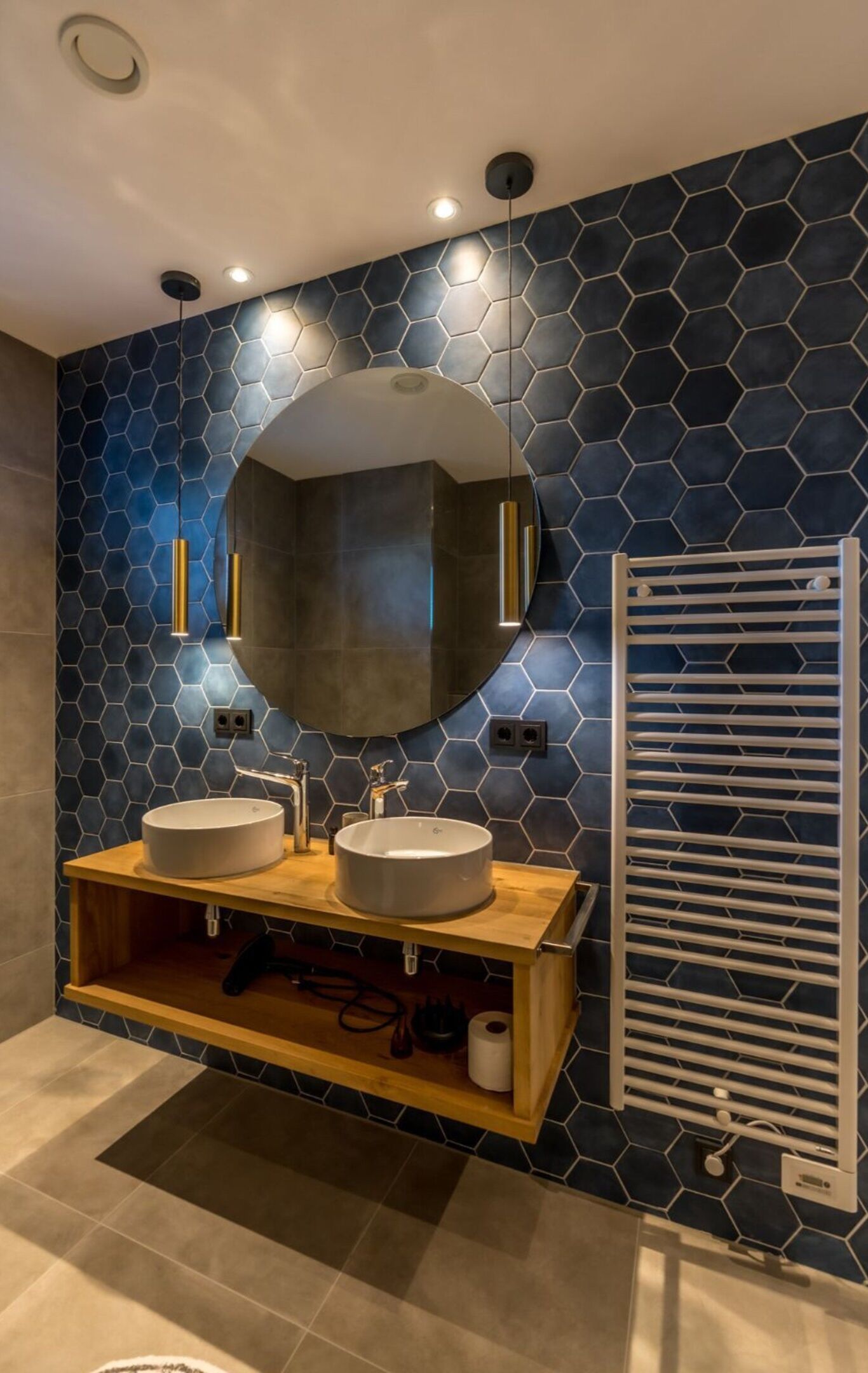 A modern bathroom with two sinks, a large mirror, and a towel rack.