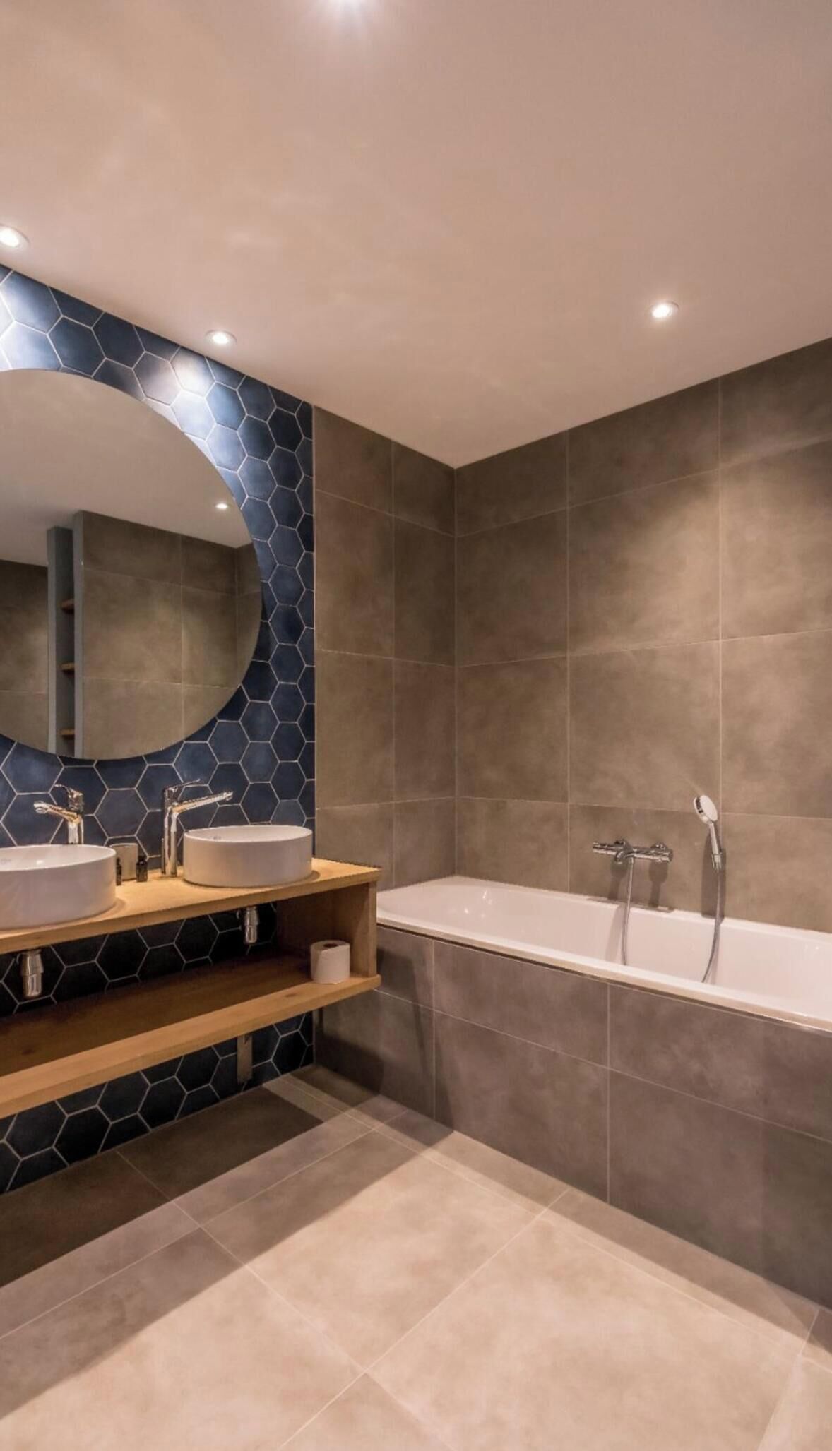 A modern bathroom with two sinks, a large mirror, and a freestanding bathtub.