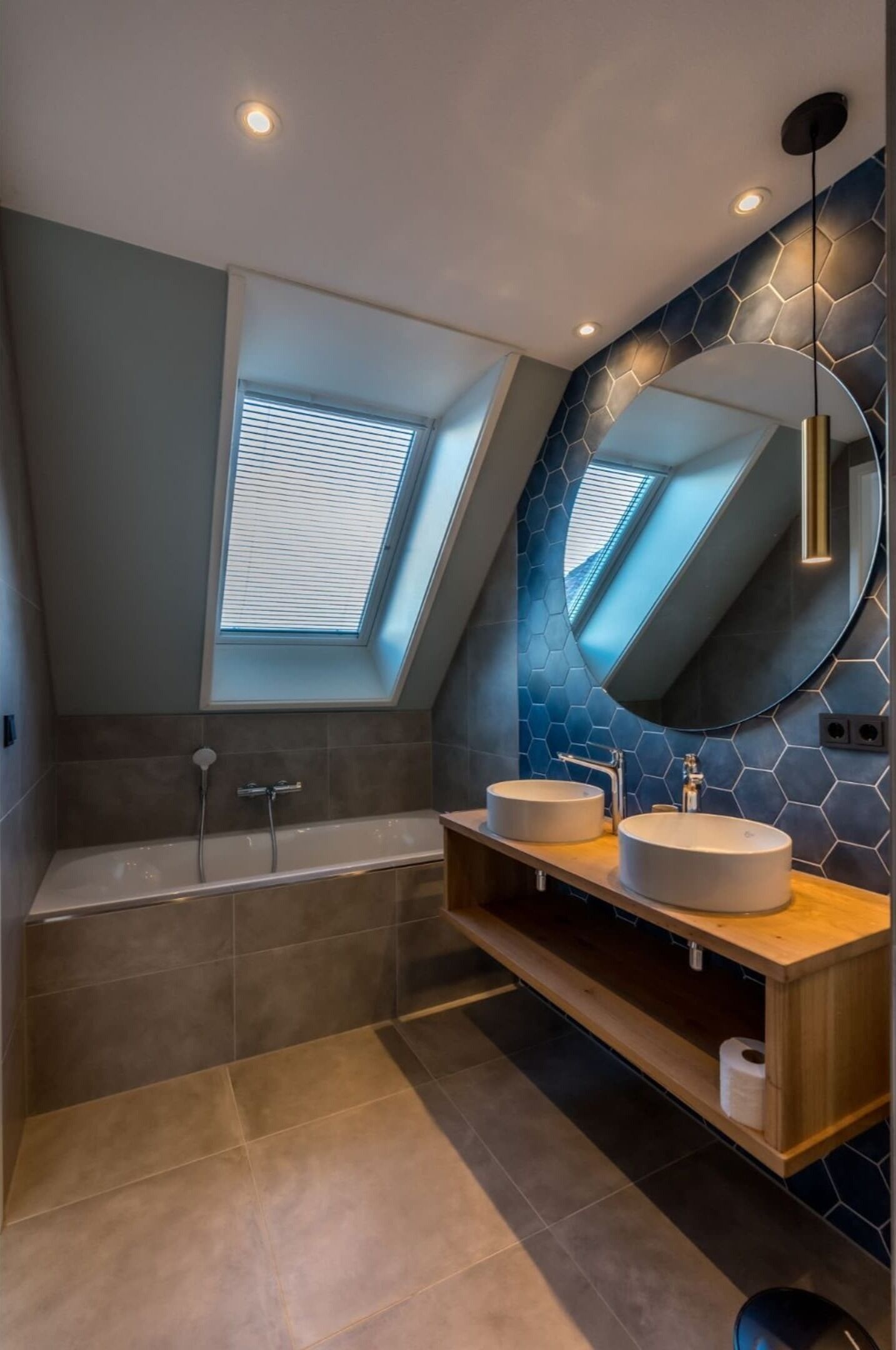 A modern bathroom with a skylight, two sinks, and a large mirror.