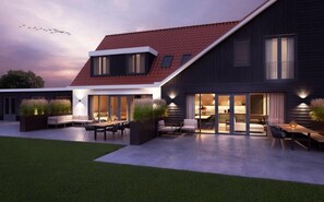 A modern house with a sloped roof, large windows, and outdoor seating areas. - Modern Villa in De Cocksdorp Near the Beach (De Cocksdorp)