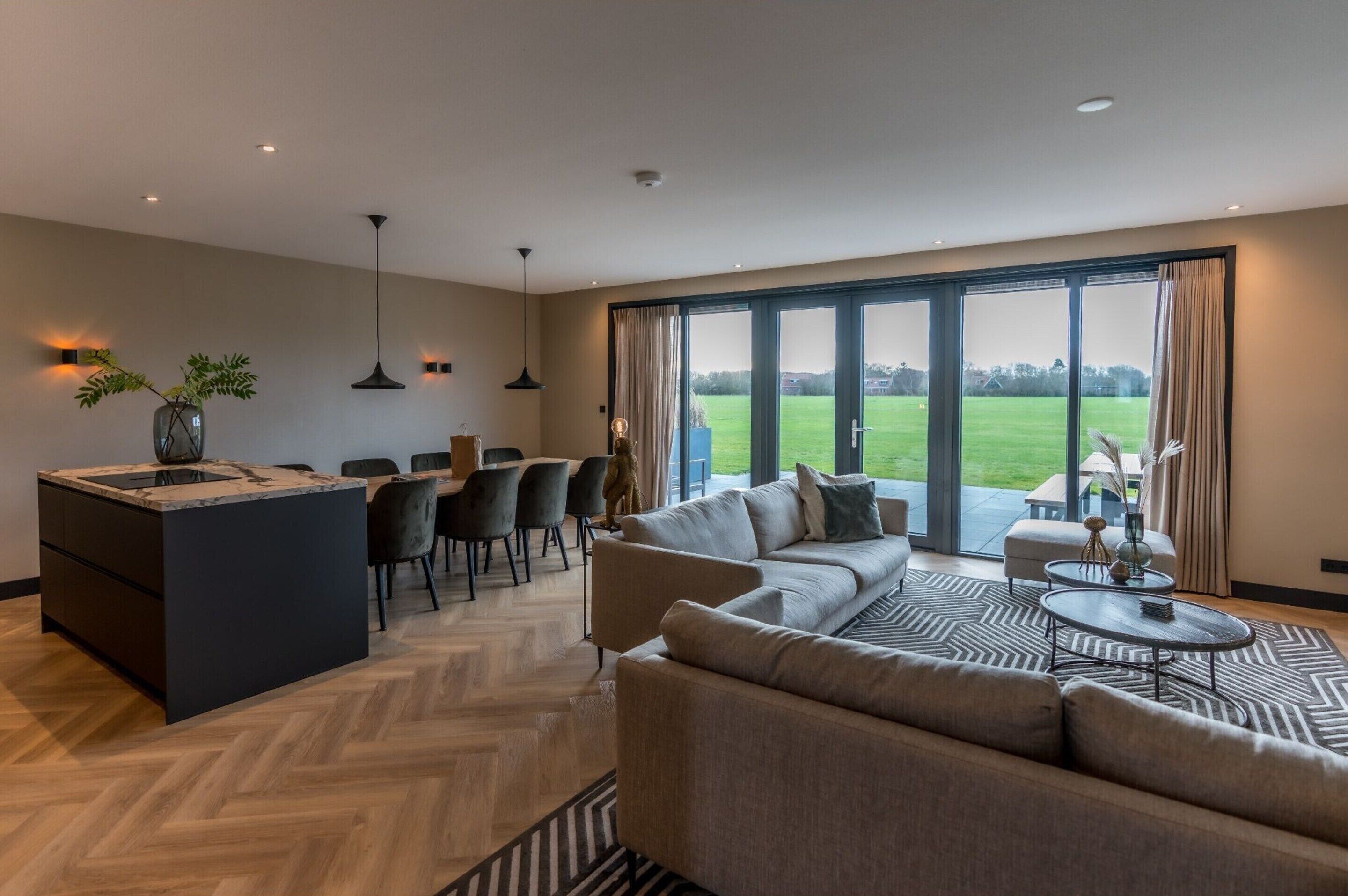 Een moderne woonkamer met een bank, salontafel en eethoek.