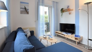 Ein modernes Wohnzimmer mit einer Couch, einem Fernseher und einem kleinen Tisch.