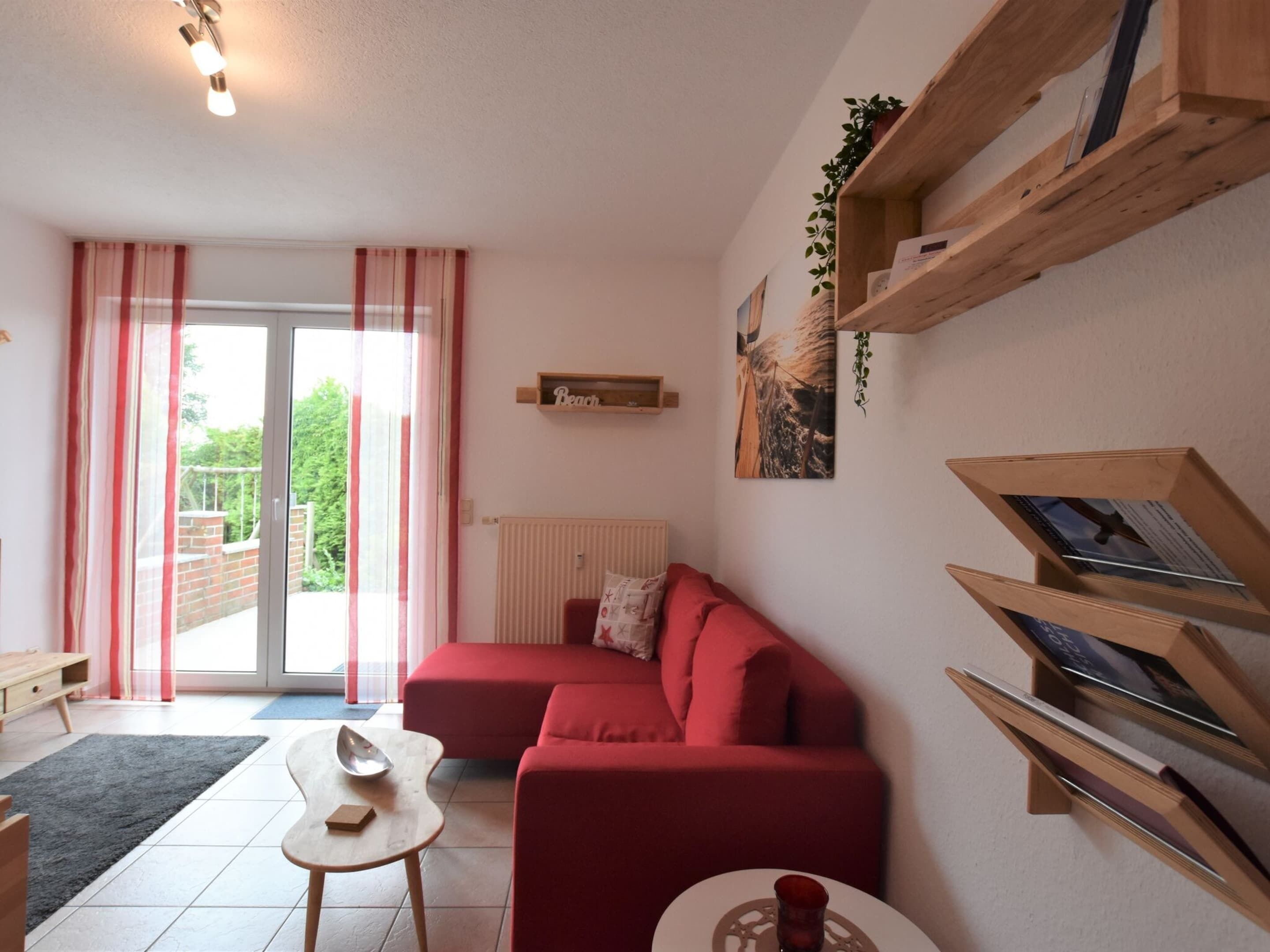 Ein Wohnzimmer mit einem roten Sofa, einem kleinen Tisch und einem Bücherregal.