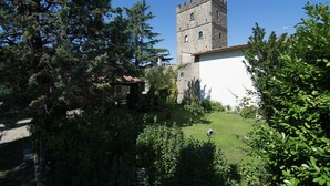 A historic stone tower adjacent to a white building with a garden in the foreground. - Lovely Estate not far From Florence With Olives Trees (Figline e Incisa Valdarno)