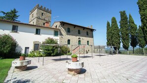 A courtyard with a stone building featuring a tower, potted plants, and a clear sky. - Lovely Estate not far From Florence With Olives Trees (Figline e Incisa Valdarno)
