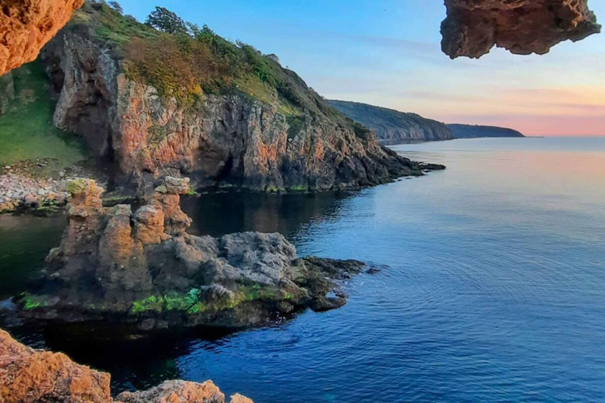 A coastal landscape with rocky cliffs and calm sea.