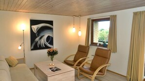 A cozy room with a sofa, two rocking chairs, a coffee table with a vase of flowers, and a painting on the wall. - 2 Person Holiday Home in Allinge (Allinge)