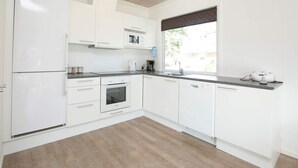A modern kitchen with white cabinets, a built-in oven, a microwave, and a coffee maker. - 8 Person Holiday Home on a Holiday Park in Blavand (Blavand)
