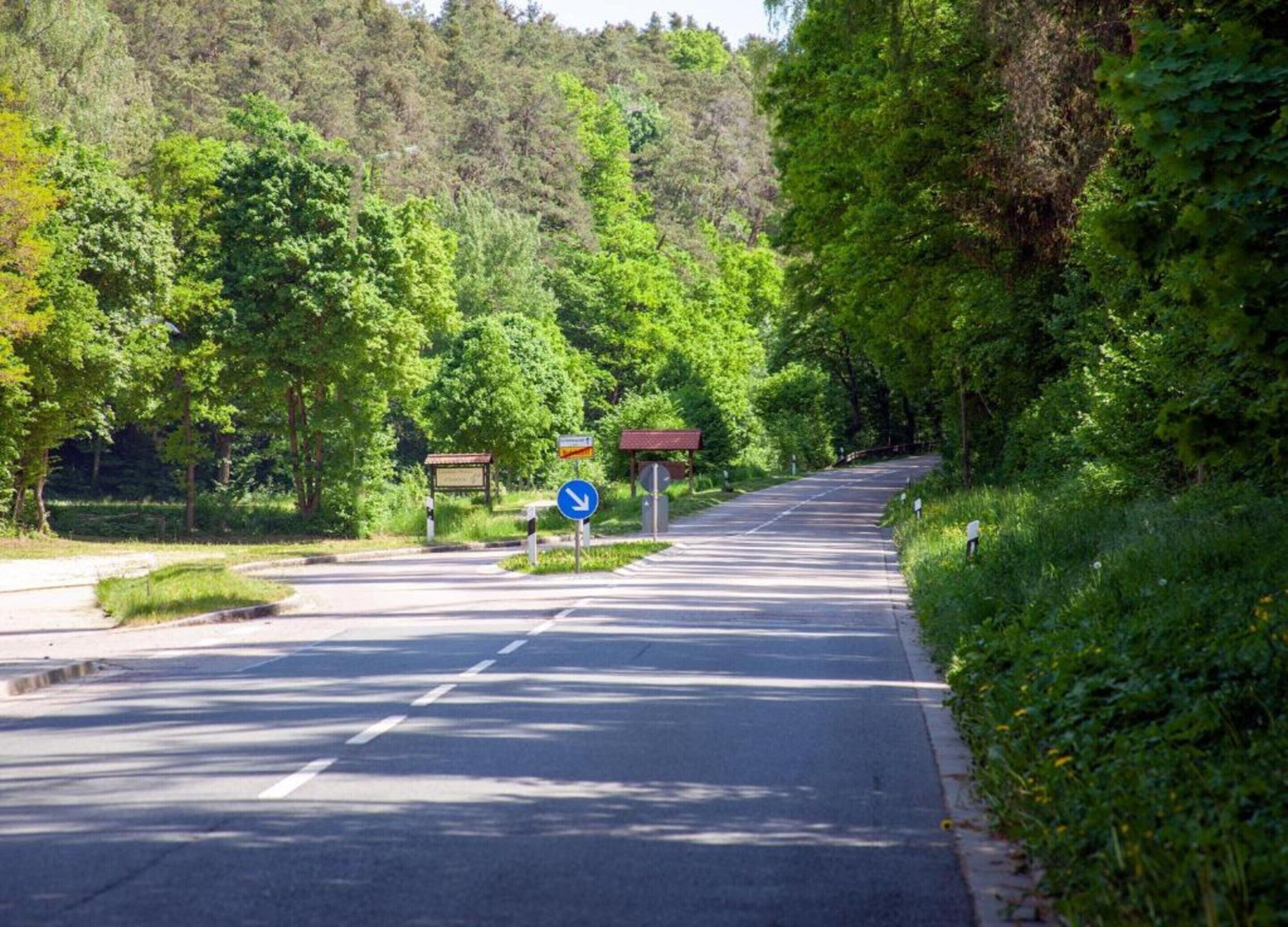 A road with a blue directional sign and a pedestrian crossing.