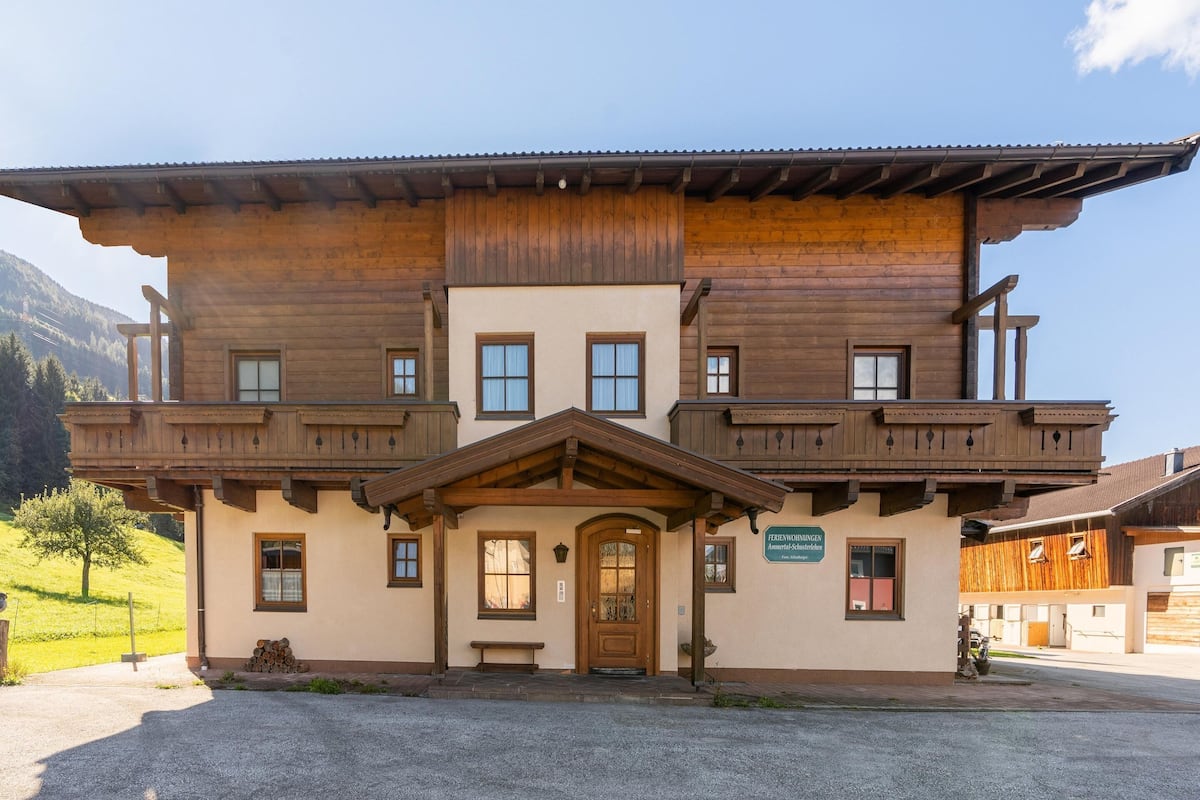 Ein zweistöckiges Holzhaus mit Balkon, Eingangstür und einem Schild, das es als Pension kennzeichnet.