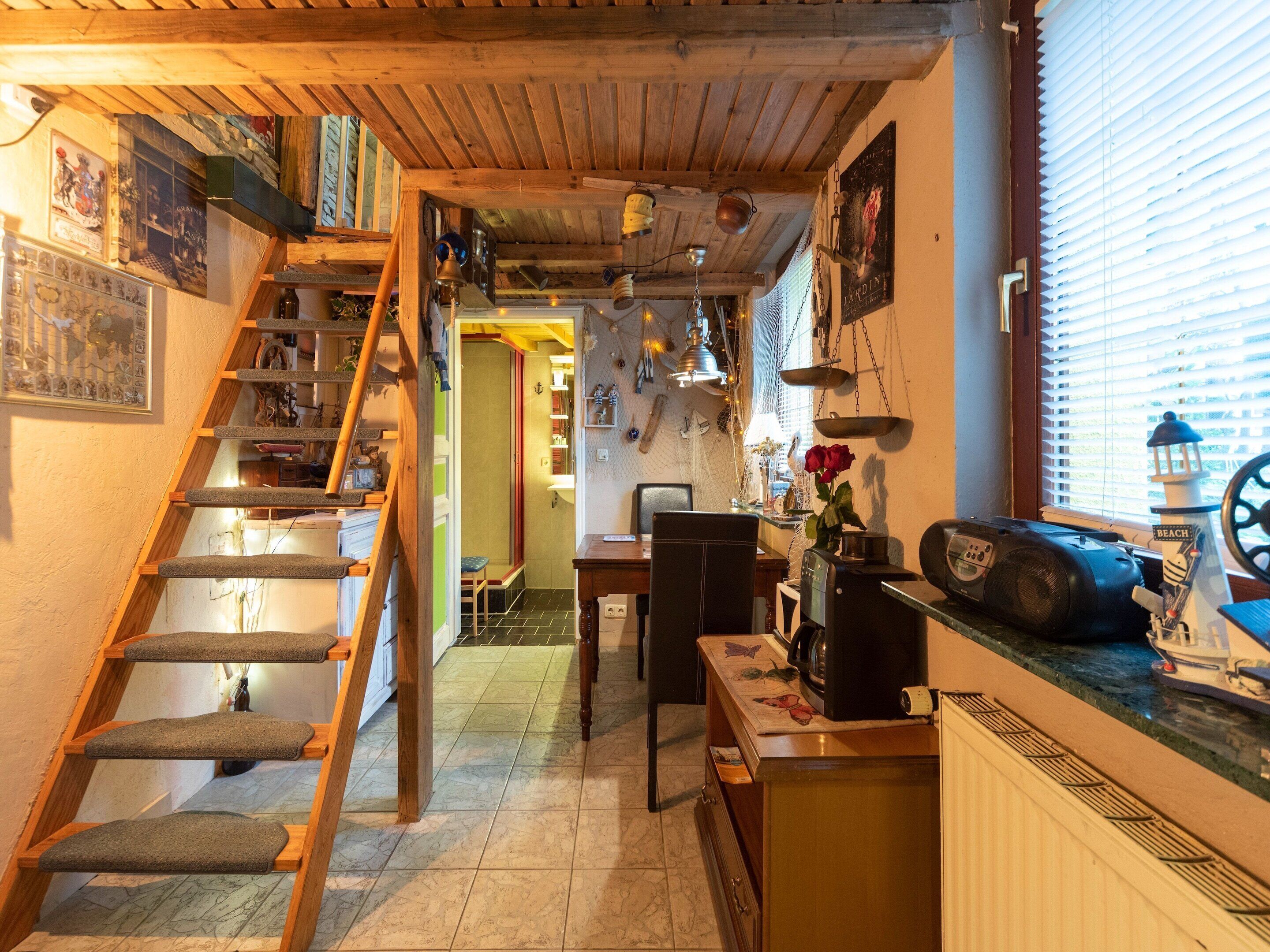 Una cocina acogedora con una escalera de madera, un comedor y una pequeña mesa con un radio y un adorno.