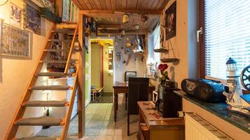 Una cocina acogedora con una escalera de madera, un comedor y una pequeña mesa con un radio y un adorno.