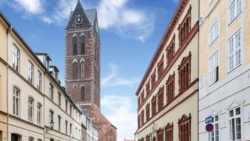 Une rue bordée de bâtiments historiques et surmontée d’un imposant beffroi.