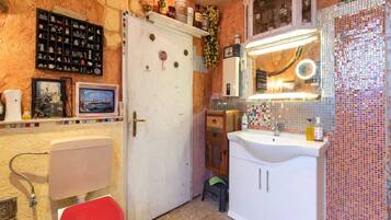 A compact kitchen with a white sink, a red toilet, and a door with a STOP sign.