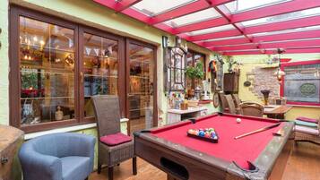 Een gezellig binnenzwembad met een houten pooltafel, comfortabele zitplaatsen en een glazen patio.