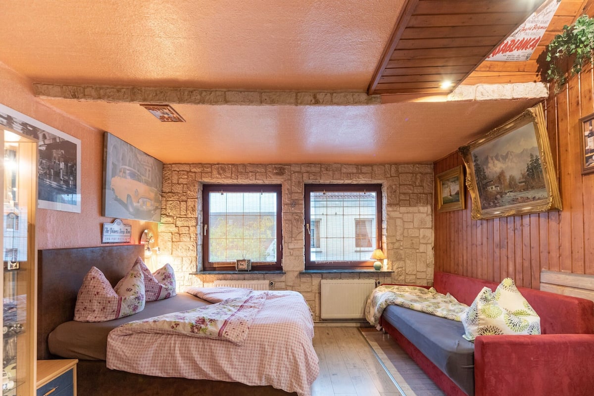 A cozy bedroom with a bed, a sofa, and a window with a view.