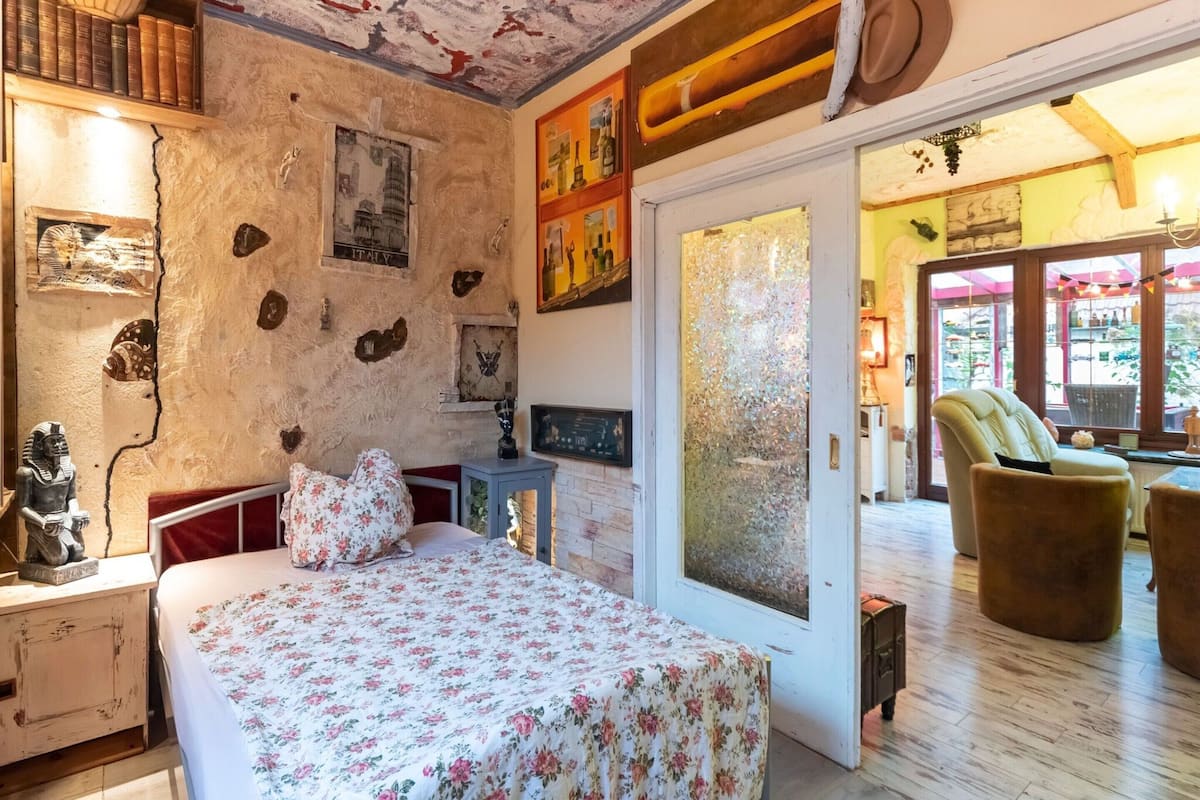 A bedroom with a bed, a nightstand, a dresser, and a window with a view of the outside.
