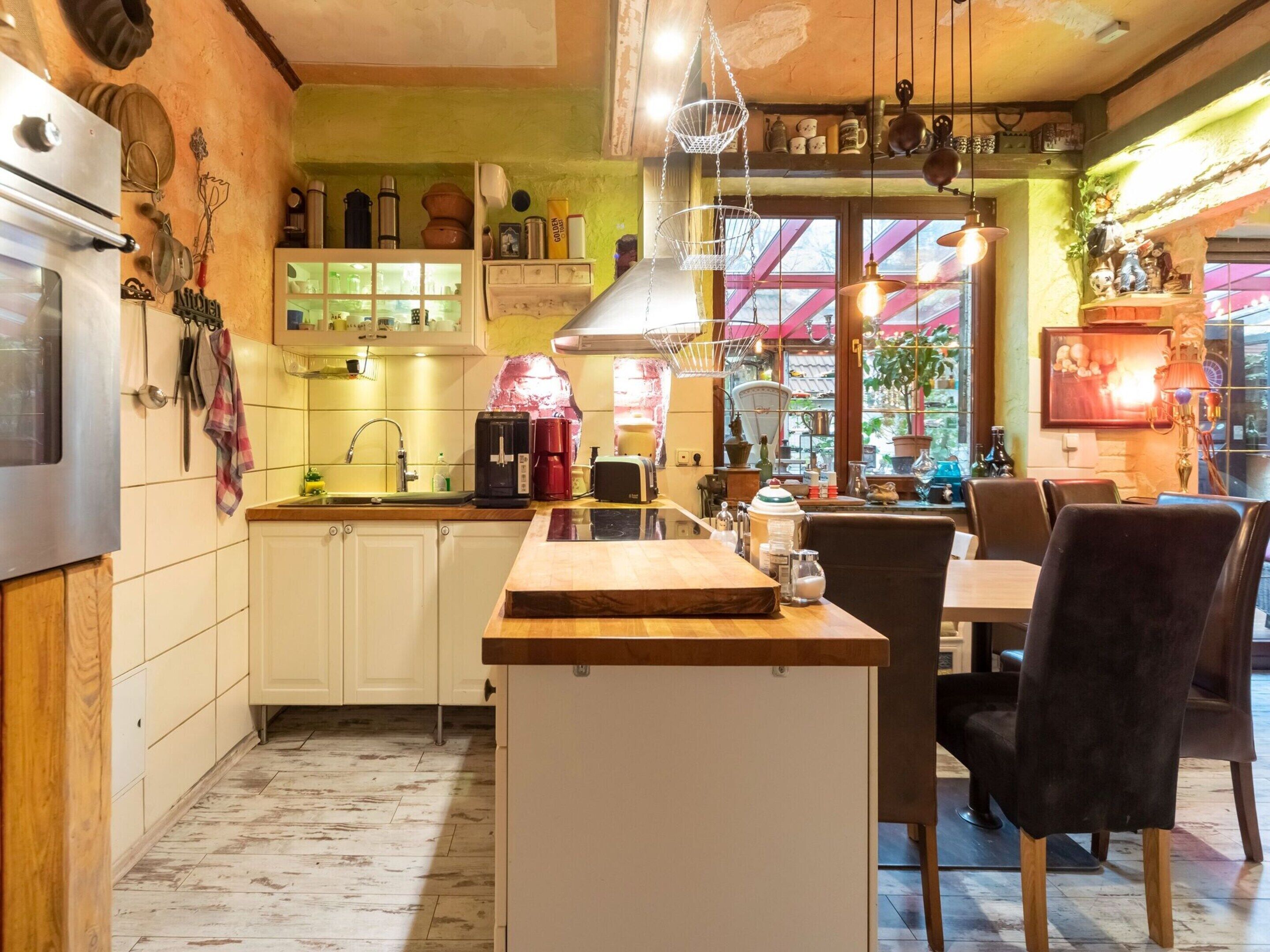 Una cocina con armarios blancos, encimera de madera y zona de comedor con sillas.