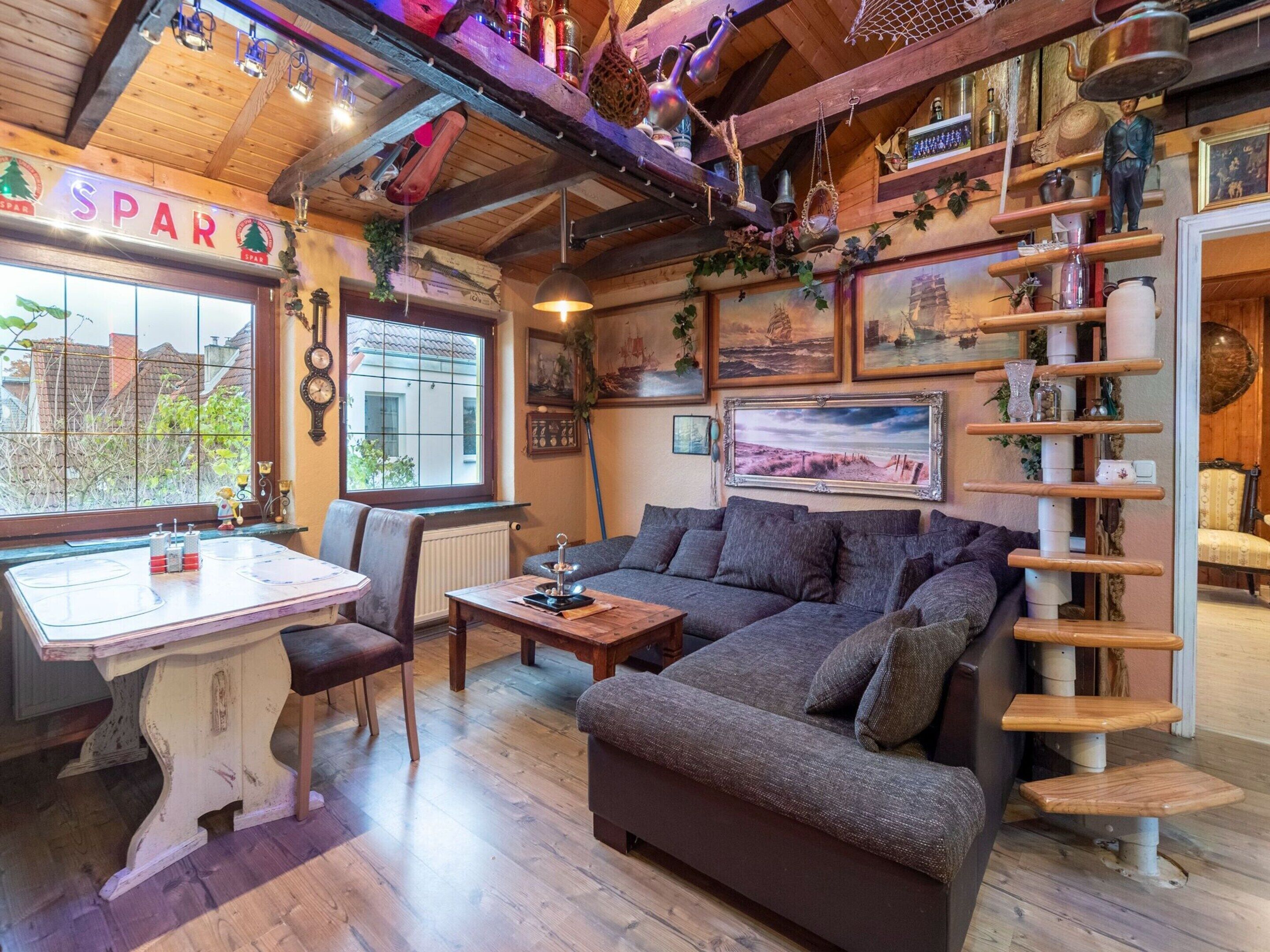 A cozy living room with a wooden ceiling, a sofa, a dining table, and a view of the outside.