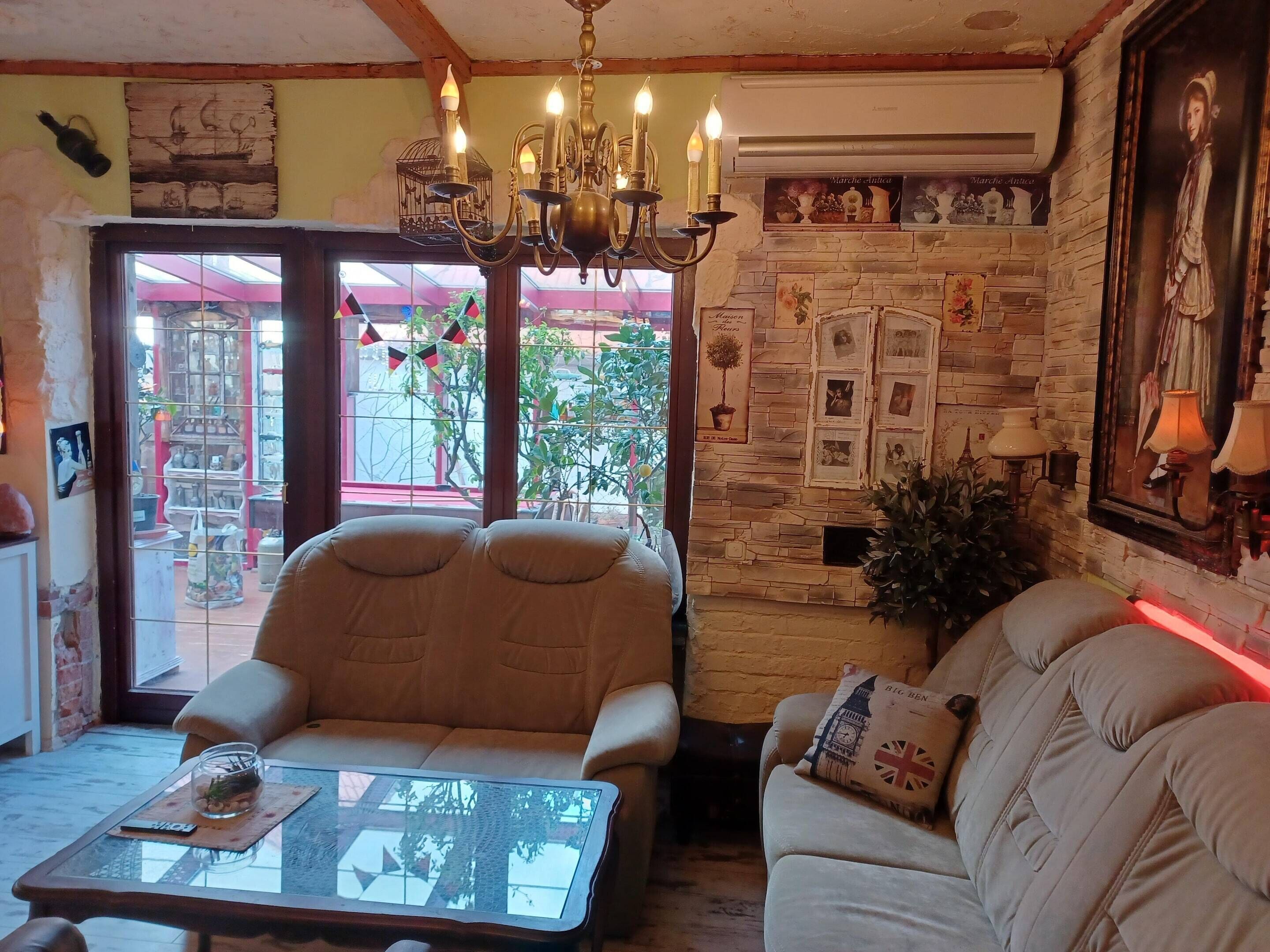 A cozy living room with a stone wall, a chandelier, and a sofa with a cushion featuring the Big Ben.