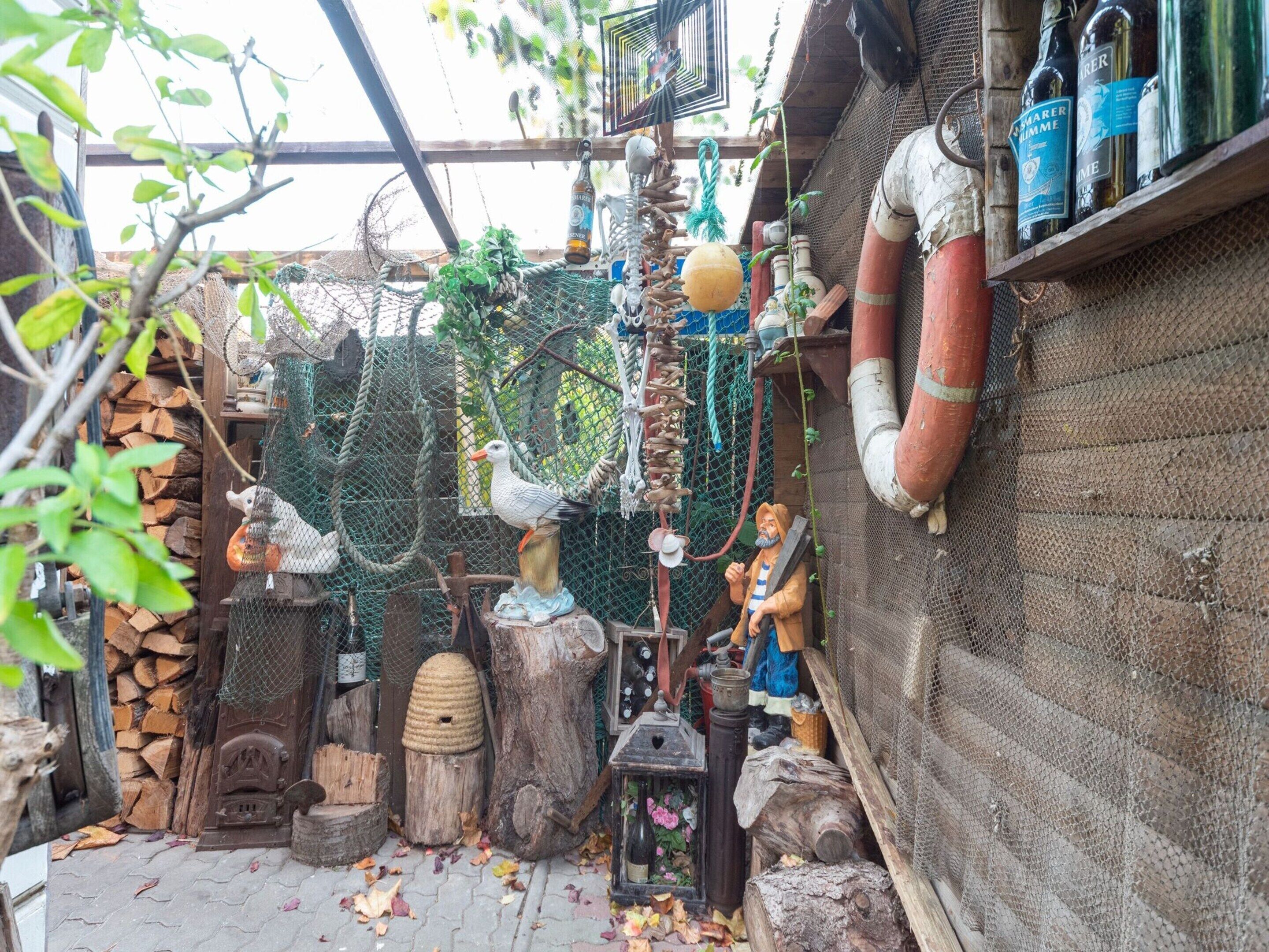 A rustic outdoor setting with wooden structures, a birdcage, and various decorative items including bottles and a lantern.