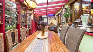 Un patio acogedor y bien iluminado con una mesa de madera, sillas de mimbre y varios adornos.