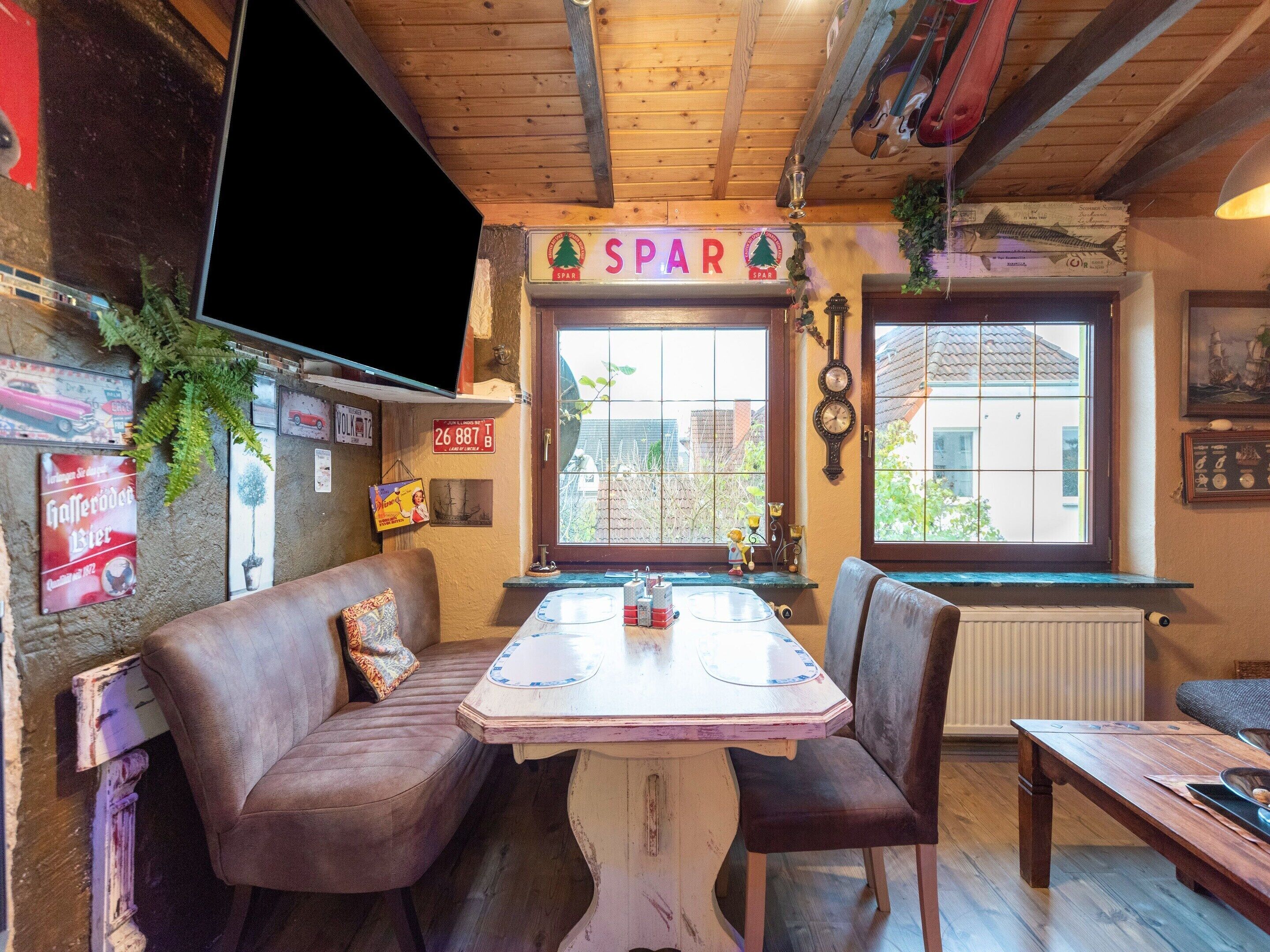 Ein gemütliches Zimmer mit Holzboden, einem Tisch mit Stühlen, einem Sofa und einem Fenster mit Blick auf Gebäude.