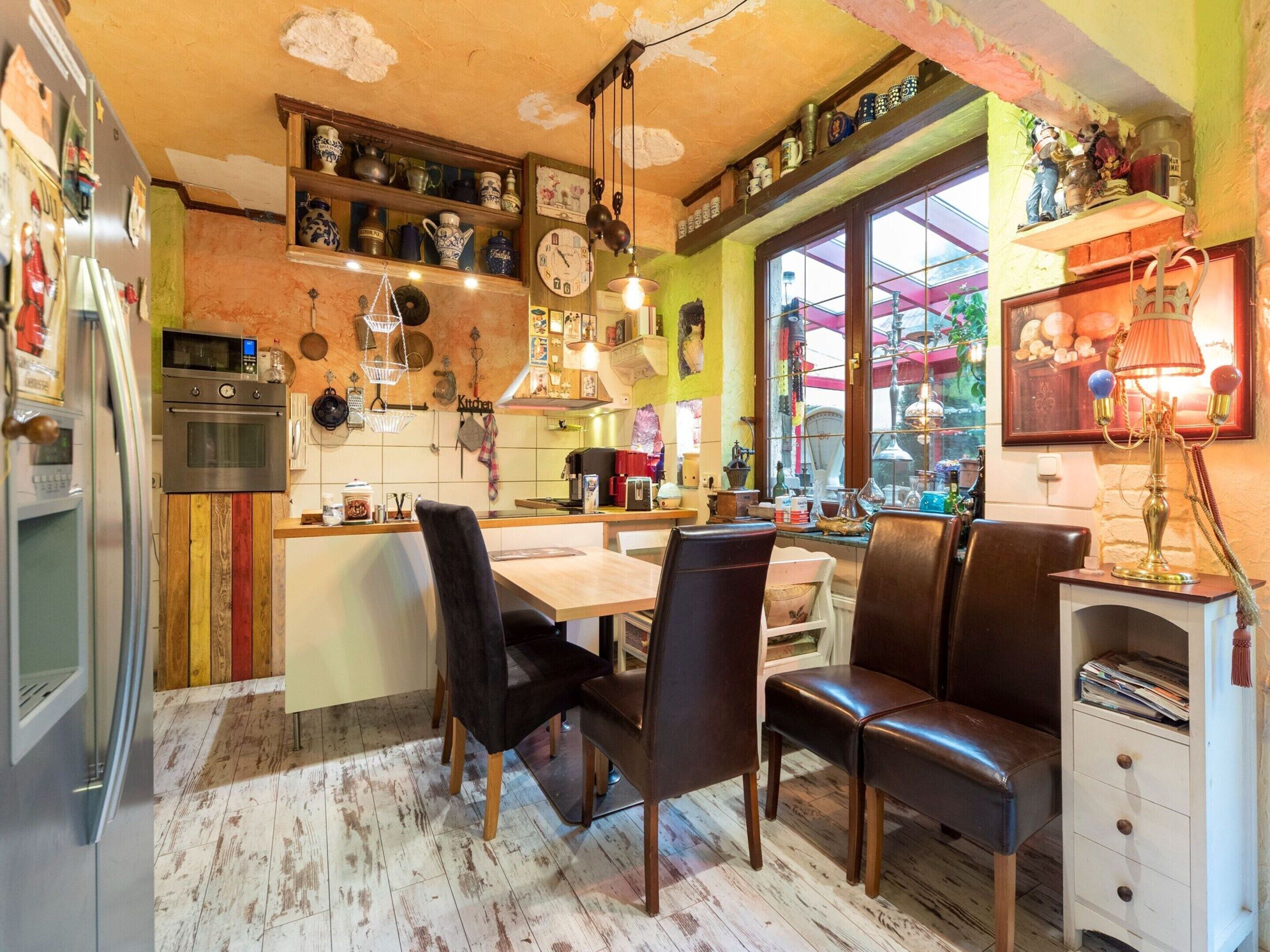 Una cocina acogedora con armarios de madera, una zona de comedor con sillas y un refrigerador.