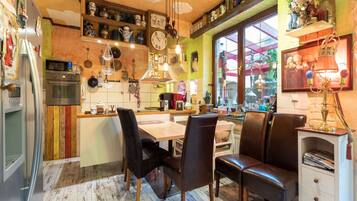 Una cocina acogedora con armarios de madera, una zona de comedor con sillas y un refrigerador.