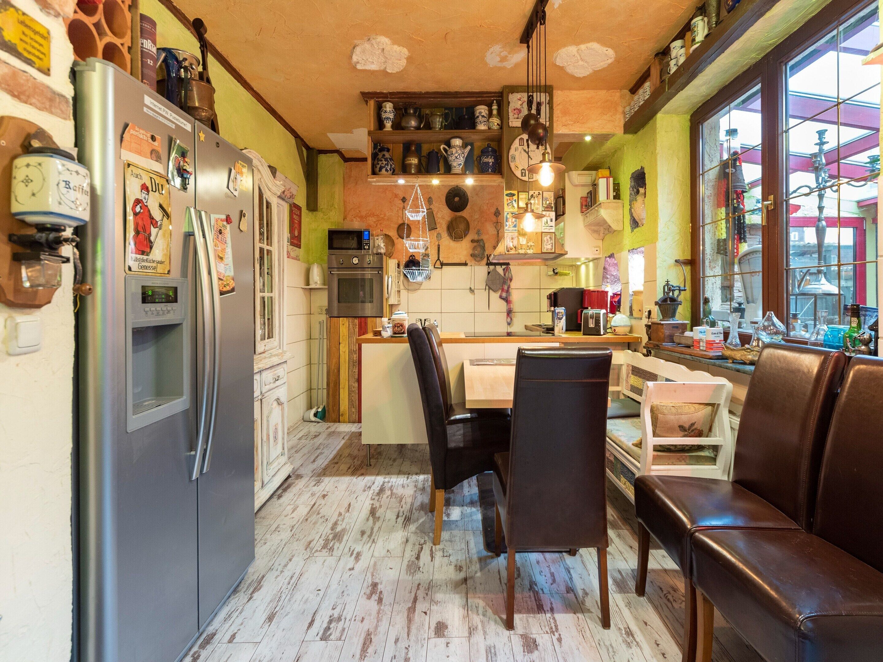 Une cuisine compacte équipée d’un réfrigérateur, d’un four et d’un four à micro-ondes. Elle comprend également un coin repas avec une table et des chaises.