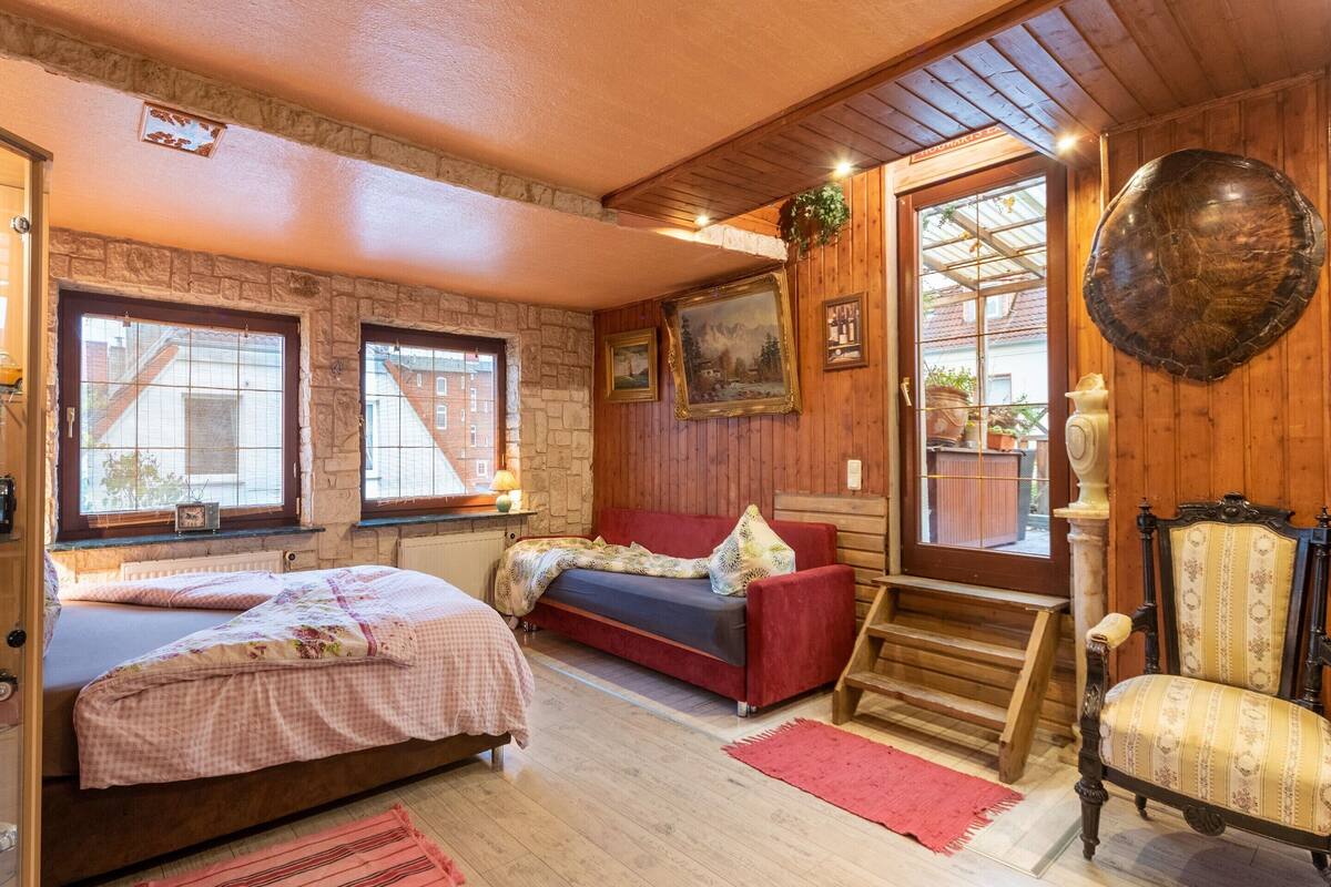 Een gezellige kamer met een bed, een bank, een stoel en een grote spiegel.