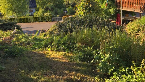 A residential property with a large garden, a fenced yard, and a view of the surrounding countryside.