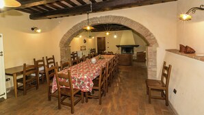 A dining area with a long table, wooden chairs, and a brick fireplace. - Elegant Apartment Only 1 Hour From Rome (Narni)
