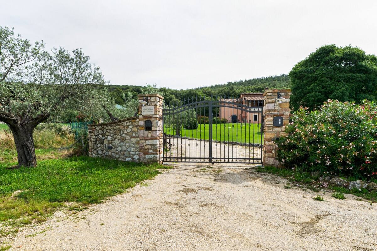A gravel driveway leading to a stone gate with a metal fence.