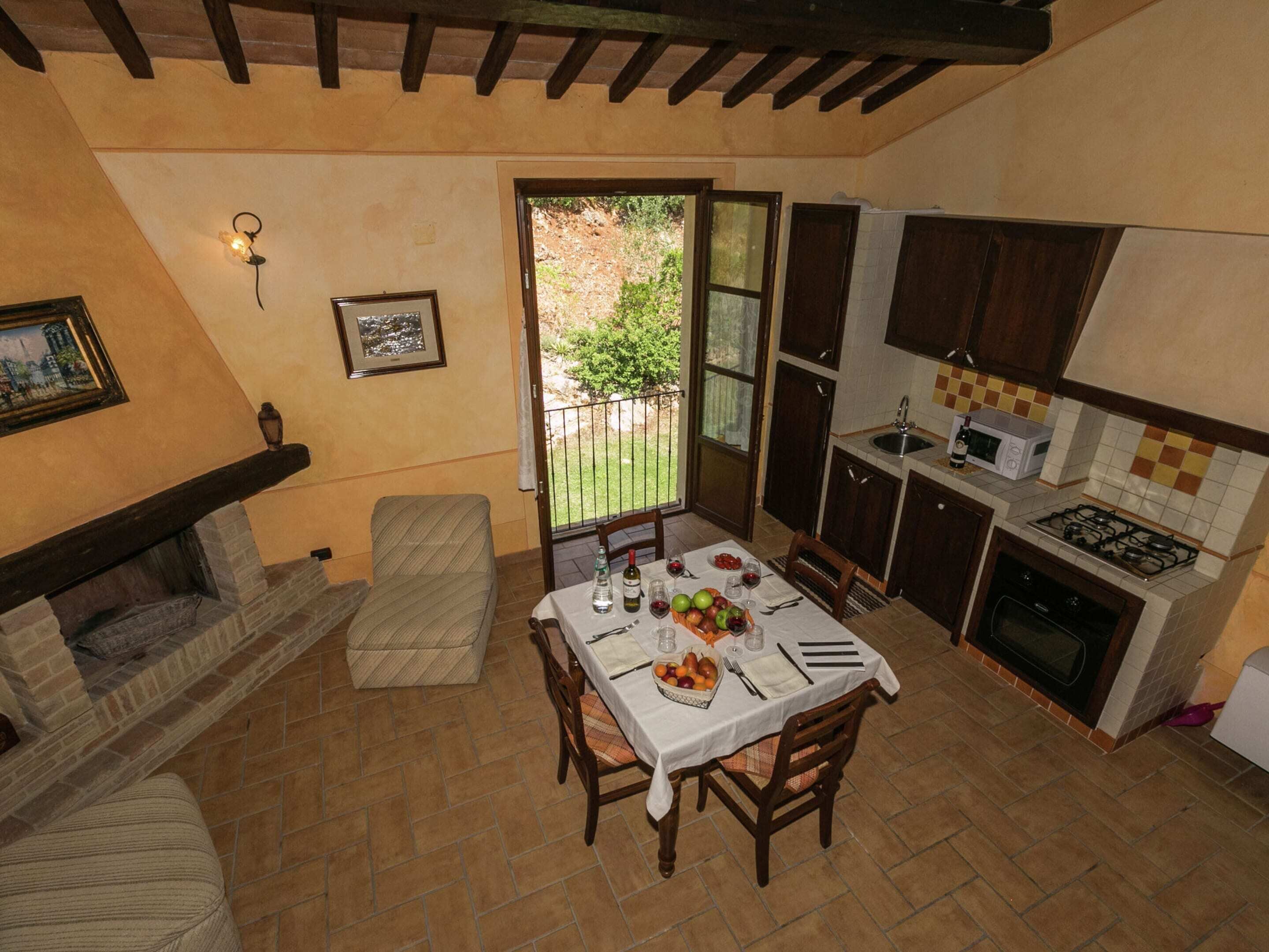 Una cocina acogedora con una mesa de comedor preparada para cuatro personas, una chimenea y vistas al jardín.