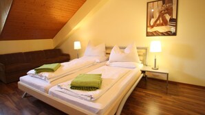 Un dormitorio con techo de madera, una cama con ropa blanca, una toalla verde, un sofá marrón y un cuadro en la pared.