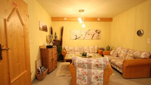 Una sala de estar acogedora con un piso de madera, un conjunto de sofá, una mesita y un aplique de pared.