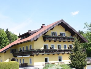 A yellow building with a red roof, multiple windows, and balconies with flower boxes. - Scenic Apartment in Krispl Salzburg With Swimming Pool (Krispl)