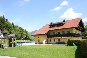 Ein großes, gelbes Gebäude mit rotem Ziegeldach, einem Spielplatz und blauem Himmel.