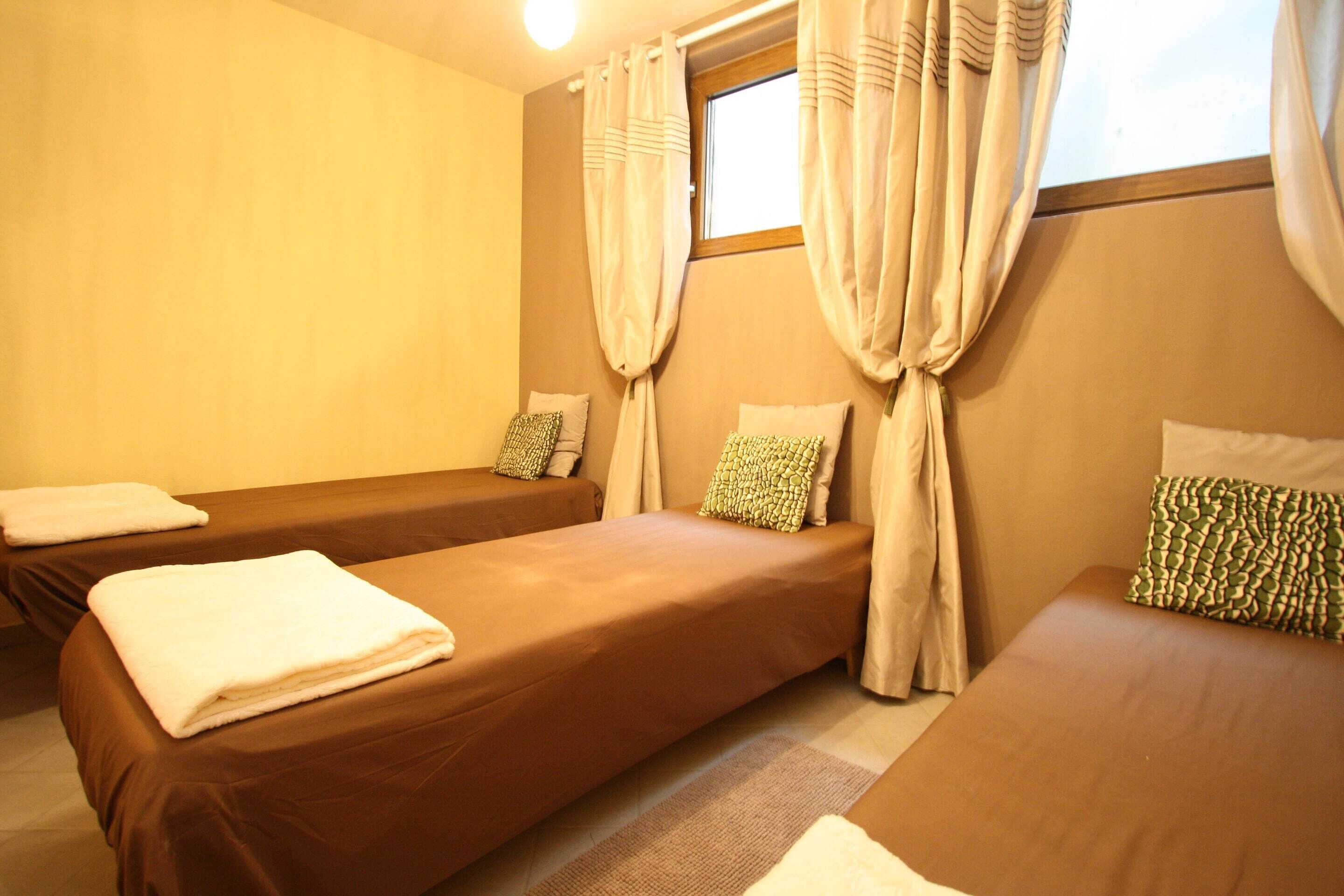 Una habitación de hotel con dos camas individuales, una ventana con cortinas y una mesita de noche pequeña.